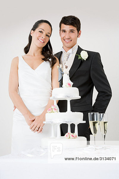 Newlyweds standing by wedding cake