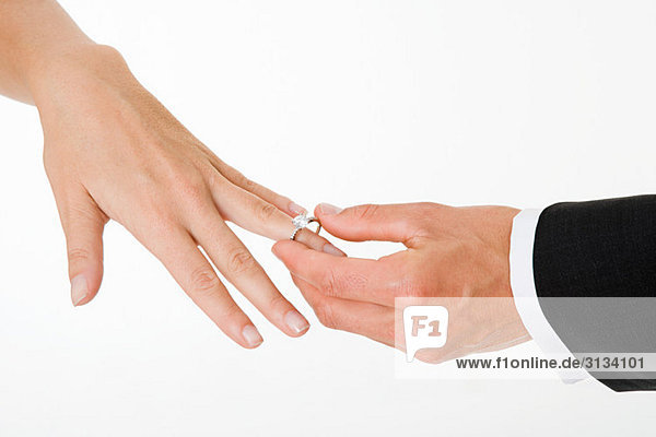 Bräutigam platziert Ring auf Bräute Finger