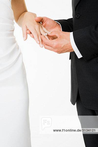 Groom placing a ring on brides finger