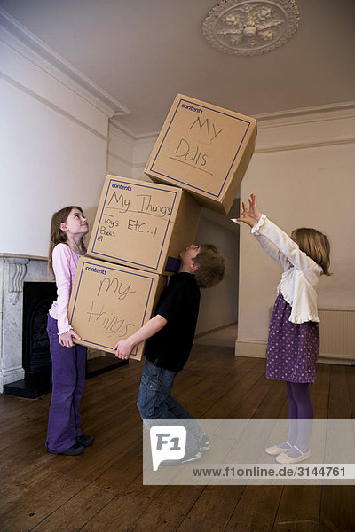 Three children moving a stack of boxes