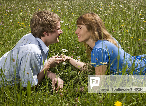 Mann  Frau im Gras liegend mit Blumen