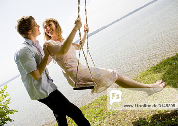 woman and man kissing on swing