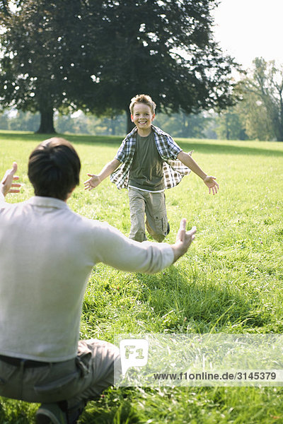A son running to his daddy in the park.