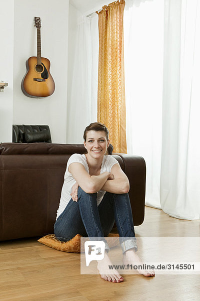 Young woman sitting on living room floor