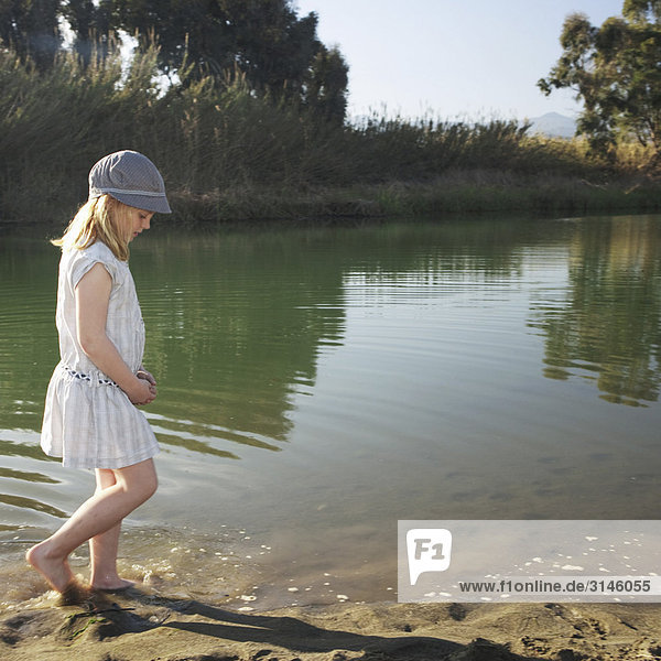 Young girl by river with feet in water