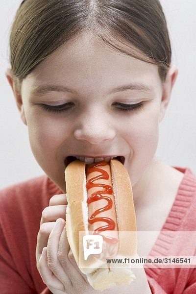 Mädchen beisst in einen Hot Dog