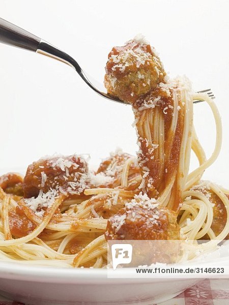 Spaghetti und ein Fleischbällchen in Tomatensauce auf einer Gabel