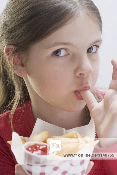 Mädchen beim Pommes Frites essen  sich den Finger leckend