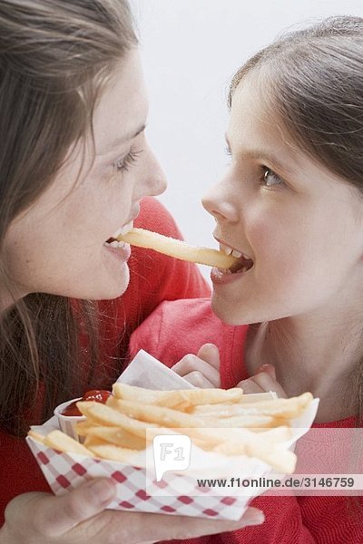 Junge Frau und Mädchen essen gemeinsam Pommes Frites