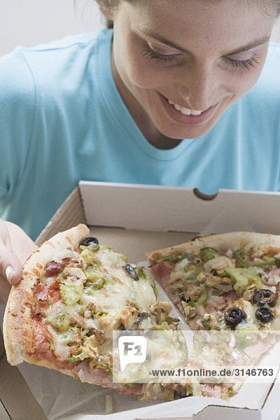 Young woman taking large slice of pizza out of box