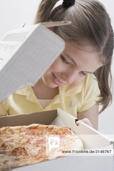Mädchen schaut in Pizza-Schachtel mit frischer Pizza
