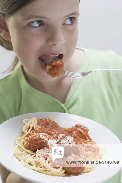 Mädchen isst Spaghetti mit Fleischklösschen
