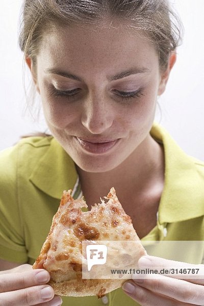 Young woman with partly eaten slice of pizza Margherita