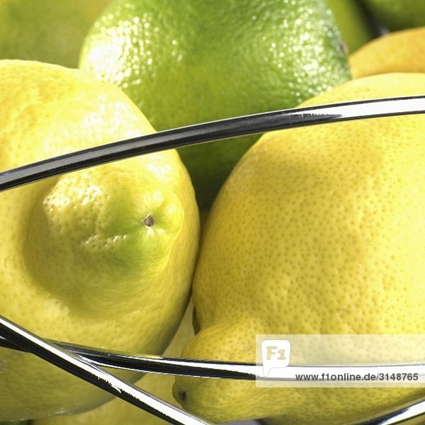Zitronen und Limetten im Drahtkorb (Close Up)