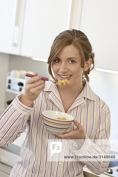 Young woman eating a bowl of cornflakes