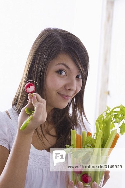 Mädchen hält rohes Gemüse und angebissenes Radieschen
