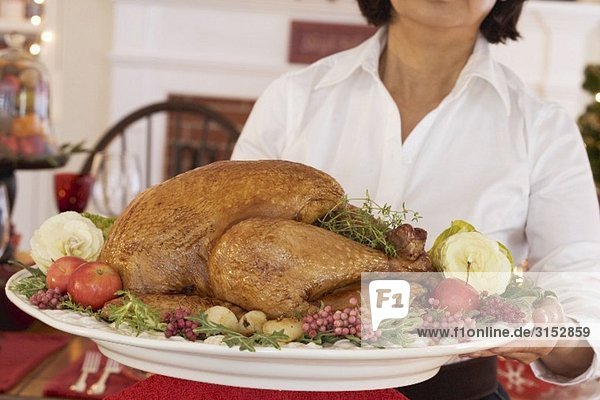 Frau serviert gebratenen Turkey zu Weihnachten