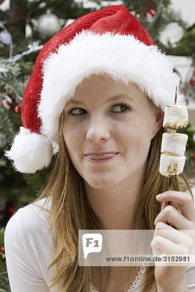 Frau mit Nikolausmütze hält Marshmallow-Spiess