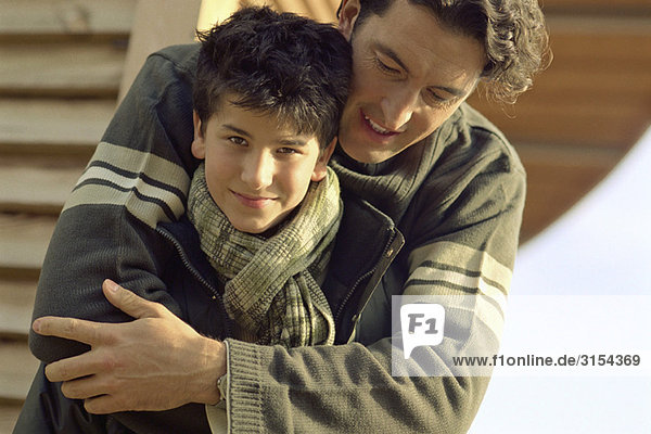 Vater umarmt Sohn  Junge lächelt vor der Kamera