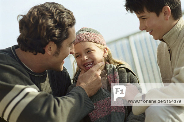 Familie zusammen im Freien  Vater lacht über die fehlenden Zähne der Tochter.