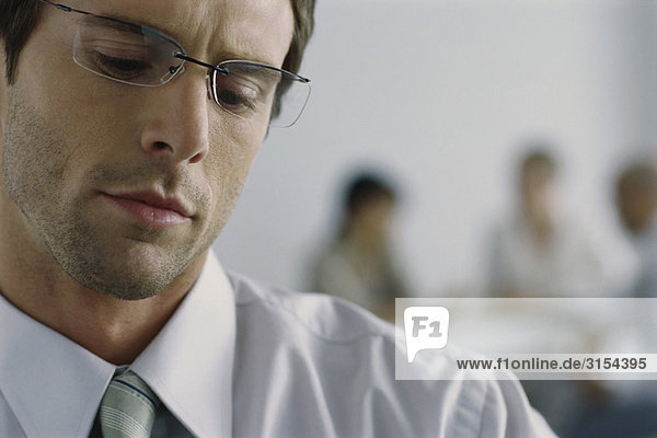 Young businessman wearing glasses  looking down with furrowed brow