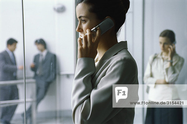 Businesswoman using cell phone in lobby  side view