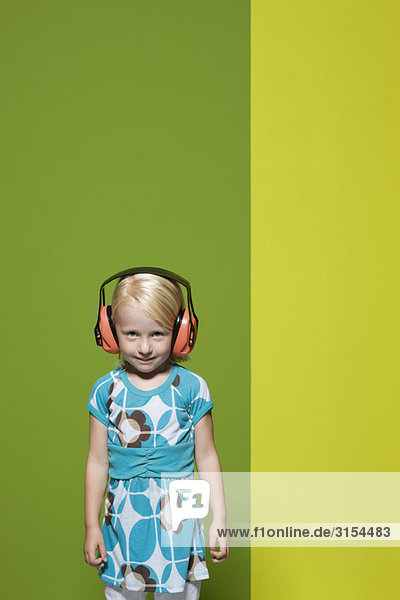 Kleines Mädchen mit schützenden Kopfhörern