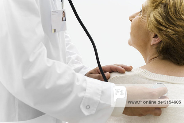 Arzt hört auf den Rücken des Patienten mit Stethoskop  abgeschnitten