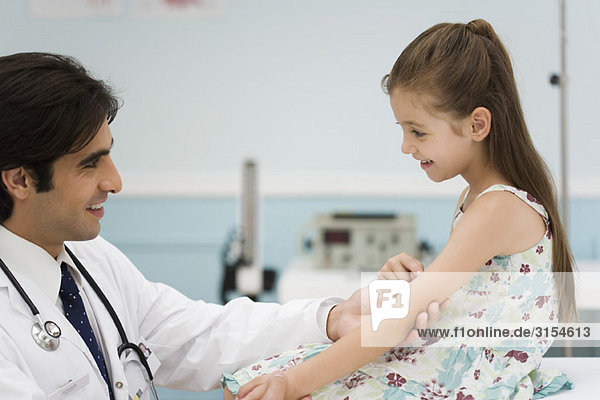 Friendly doctor examining little girl's arm