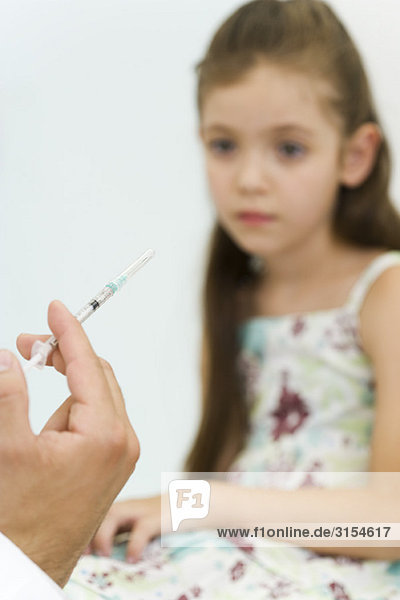 Arzt hält Spritze  Vorbereitung zur Impfung des kleinen Mädchens  abgeschnitten