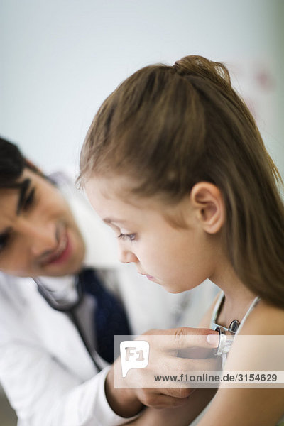 Pediatrician listening to little girl's chest with stethoscope