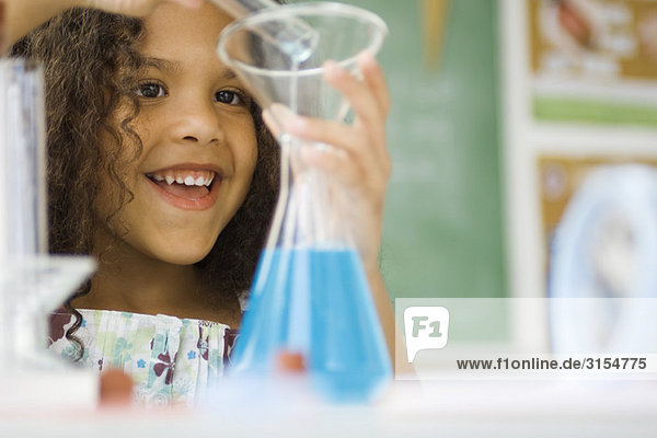 Little girl transferring liquid from test tube to beaker