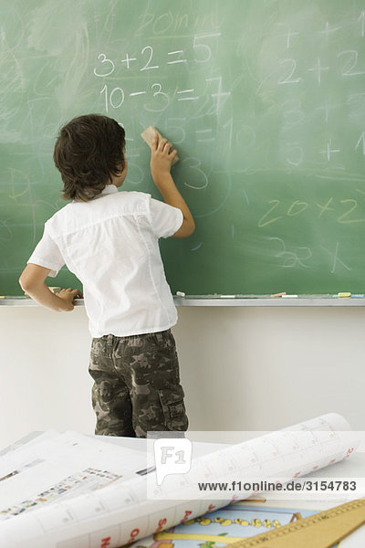 Boy erasing blackboard  rear view