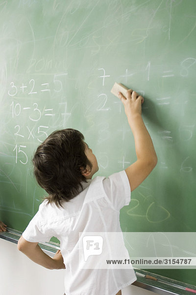 Boy erasing classroom blackboard  rear view