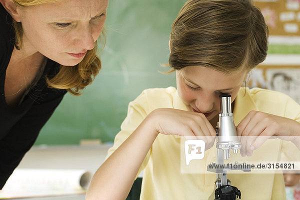 Elementary teacher watching student using microscope