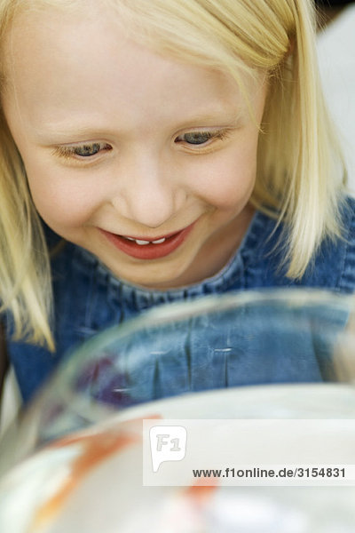 Little girl looking at goldfish in bowl  high angle view