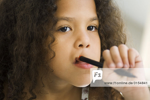 Little girl holding pen against mouth  looking away