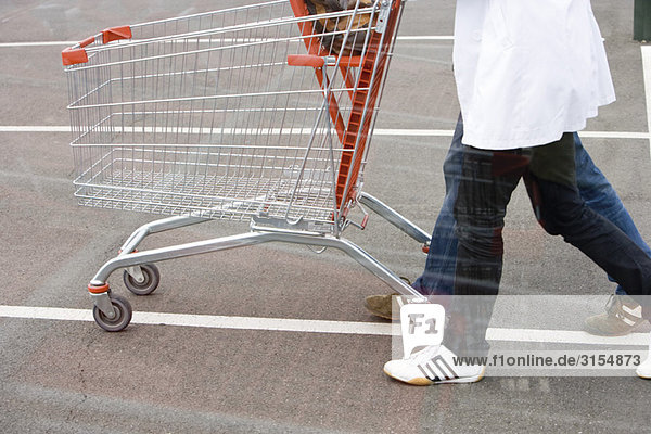 Empty shopping cart being pushed across parking lot
