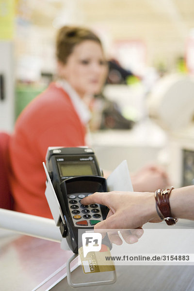 Customer entering pin into credit card reader keypad