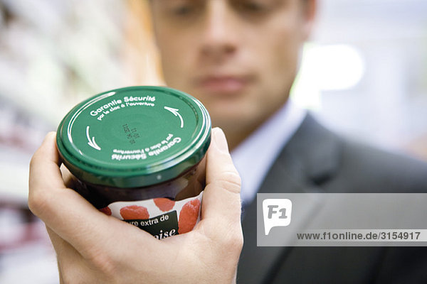 Mann liest Etikett auf Marmeladenglas