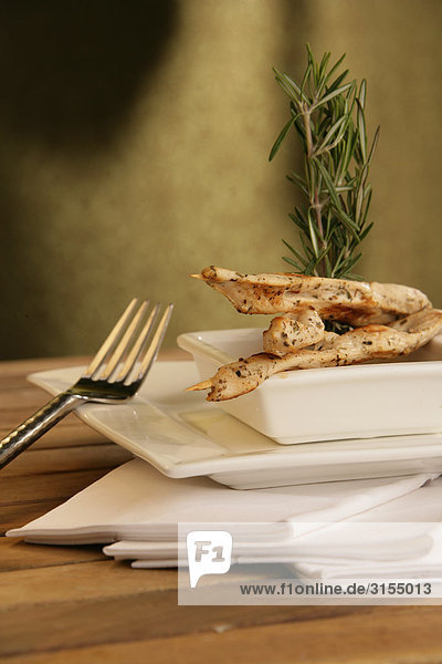 Chicken with rosemary in white dishes and a fork