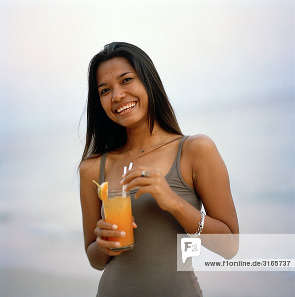 Eine junge Frau mit einem Drink am Strand  Thailand.