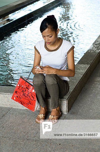 Eine junge Frau in einem Einkaufszentrum mit ihrem Handy Manila Philippinen.