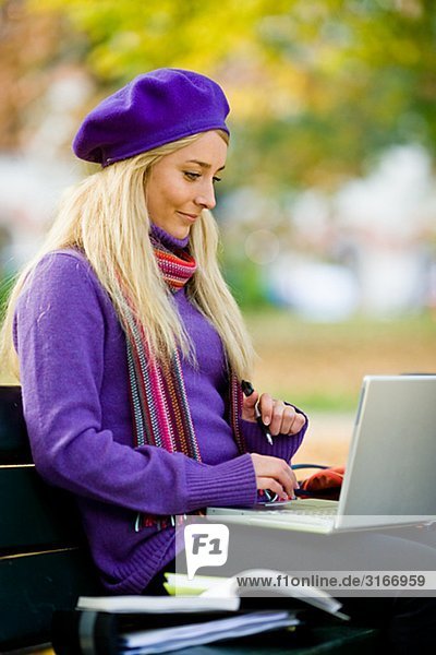 A woman sitting on bench in a park using a laptop Stockholm Sweden.