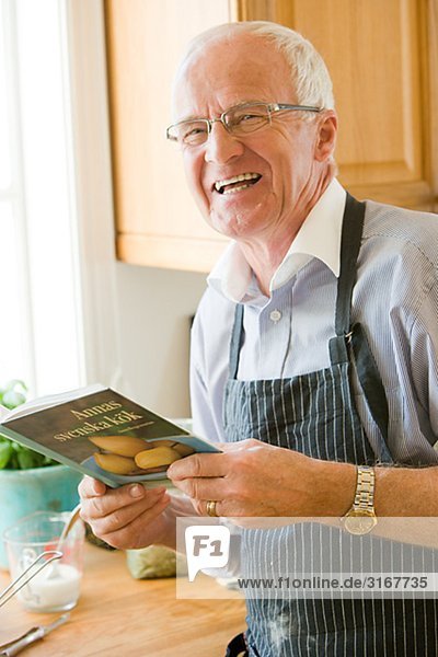 Senior man about to cook reading a cookbook  Sweden.