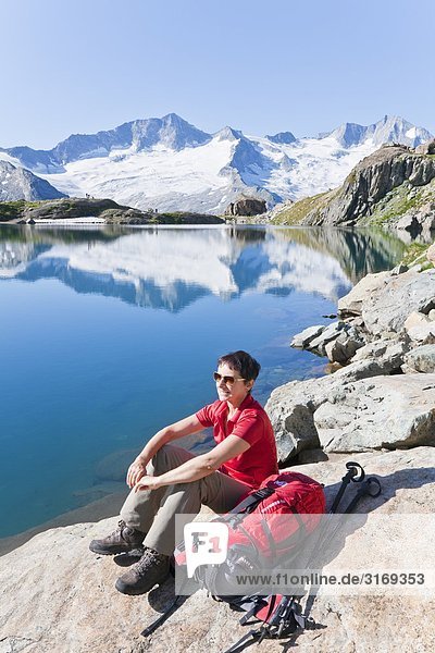 Frau an einem Bergsee sitzend Tirol Österreich Erhöhte Ansicht