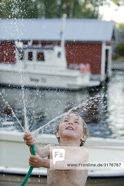 Ein Junge mit einem Wasserschlauch  Schweden.