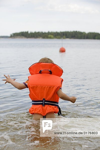Junge mit einer Schwimmweste im Wasser  Schweden.
