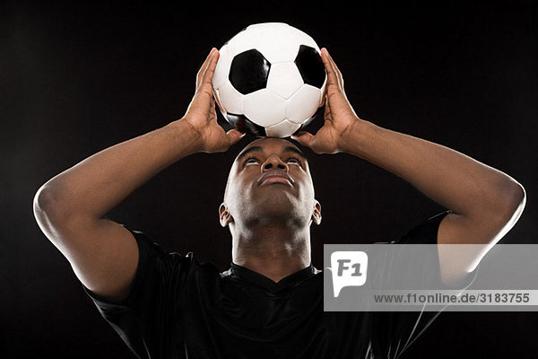 Mann  der einen Fußball auf dem Kopf balanciert