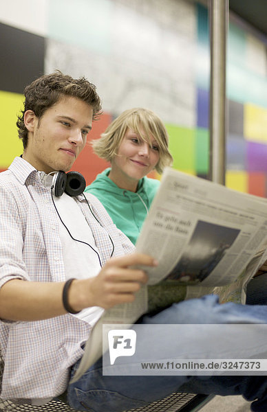 Teenager couple readung newspaper at underground  low-angle view